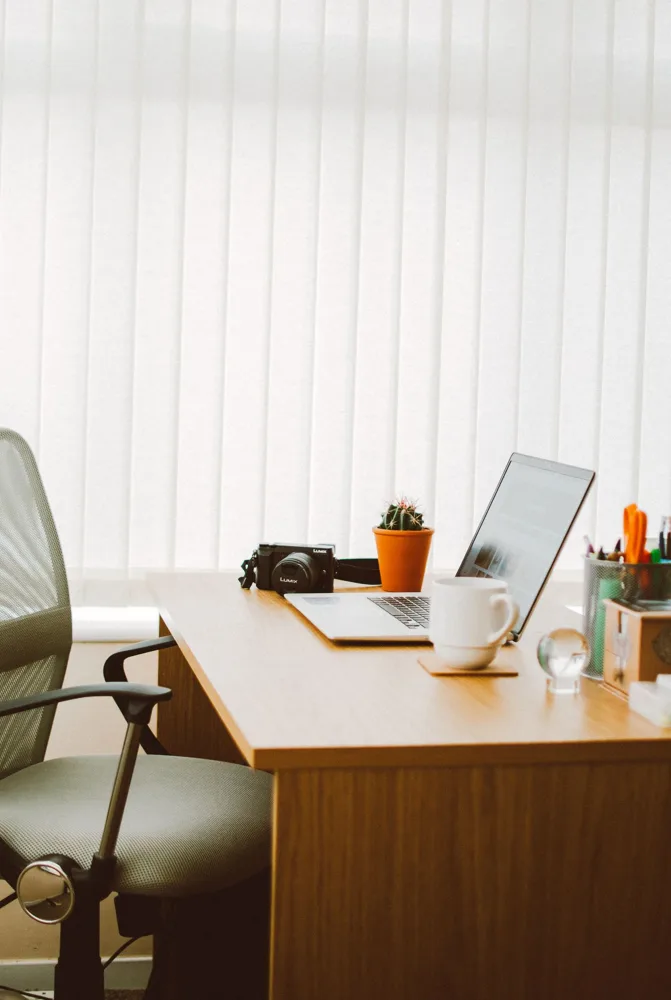 A tidy home office desk with a laptop, coffee mug and small cactus