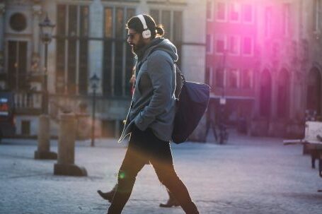 Headphones - Man in Gray Hooded Jacket Walking on Gray Bricks Pavement