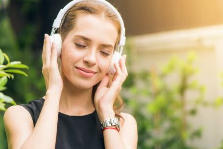 Headphones - Woman Wearing Black Sleeveless Dress Holding White Headphone at Daytime