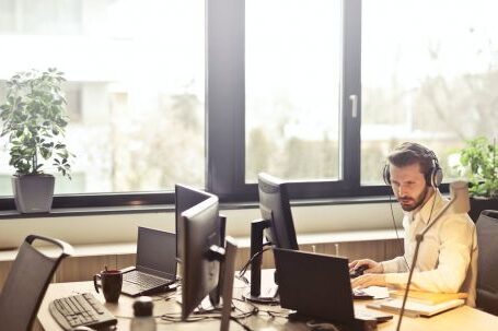 Tech Support - Man With Headphones Facing Computer Monitor