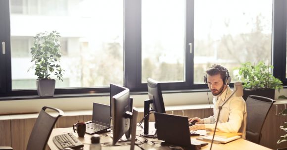 Tech Support - Man With Headphones Facing Computer Monitor