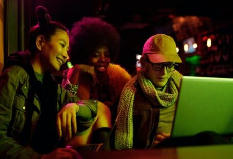 Secure Computer - Woman in Black and White Dress Sitting Beside Woman in Green and Black Dress