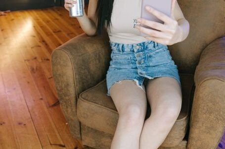 International Content Streaming - A Woman Sitting on the Chair while Holding Her Mobile Phone