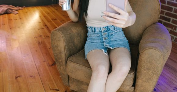 International Content Streaming - A Woman Sitting on the Chair while Holding Her Mobile Phone