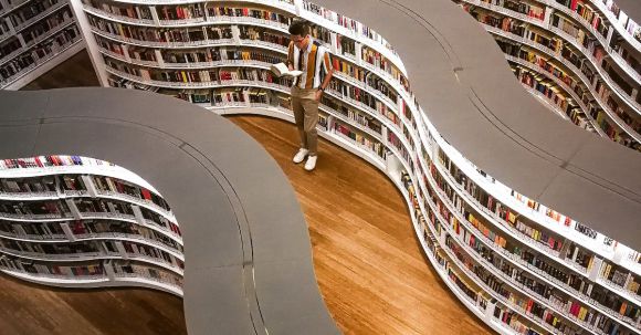 E-Readers - Man Standing Inside Library While Reading Book