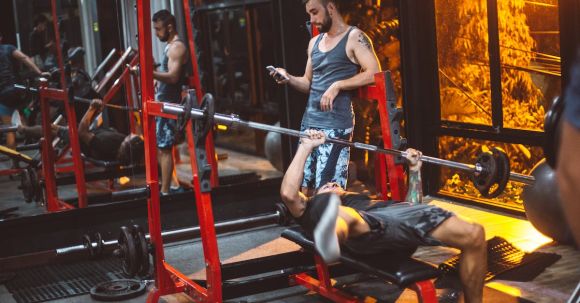 Fitness Apps - Sporty fitness trainer and man lifting barbell