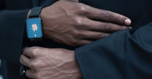 Wearable Fashion - Anonymous person adjusting suit of unrecognizable African American gentleman in elegant outfit with modern smart watch