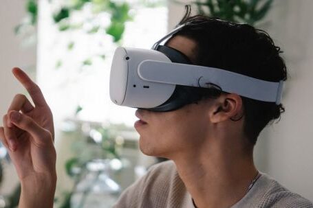 VR Innovations - Side view of concentrated young guy in casual clothes experiencing virtual reality in modern headset at home