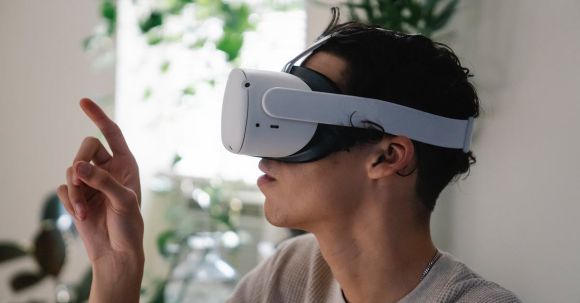 VR Innovations - Side view of concentrated young guy in casual clothes experiencing virtual reality in modern headset at home