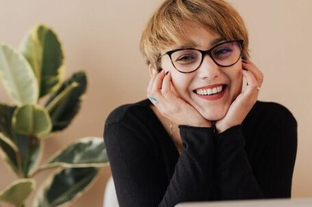 Smart Doorbell - Cheerful woman smiling while sitting at table with laptop