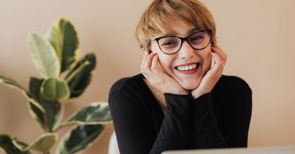 Smart Doorbell - Cheerful woman smiling while sitting at table with laptop