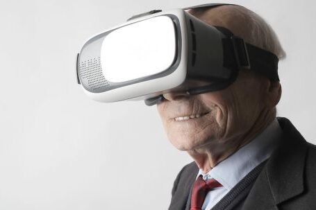 Virtual Reality Headsets - Smiling elderly gentleman wearing classy suit experiencing virtual reality while using modern headset on white background