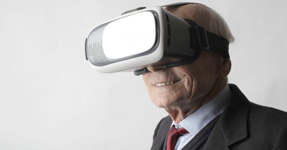 Virtual Reality Headsets - Smiling elderly gentleman wearing classy suit experiencing virtual reality while using modern headset on white background