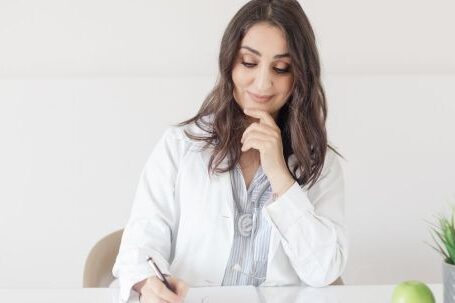 Medical Wearables - A woman in a white lab coat writing on a piece of paper