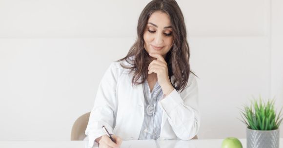 Medical Wearables - A woman in a white lab coat writing on a piece of paper