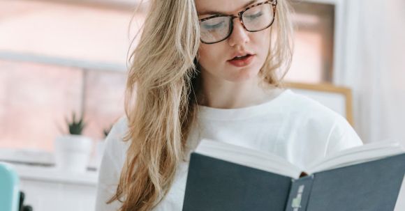 Smart Kitchen Appliances - Focused woman reading book in kitchen