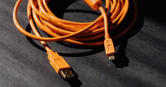 Tablet Battery Life - From above of orange usb to micro usb cable twisted into ring placed on black board