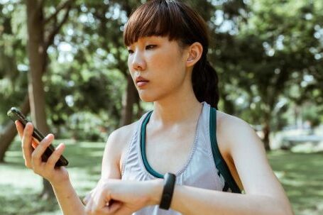 Wearable Sleep Monitors - Concentrated young Asian woman using smartphone in park